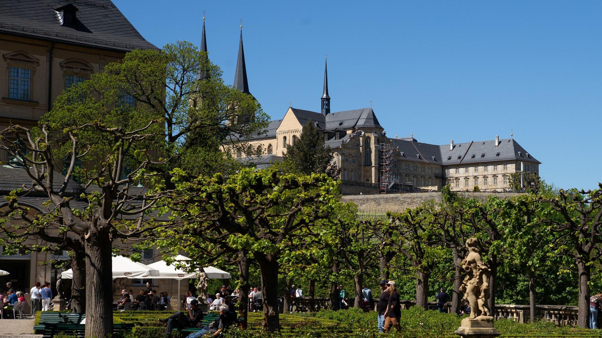 Blick auf ein Klostern, darunter ein Biergarten in einem Park