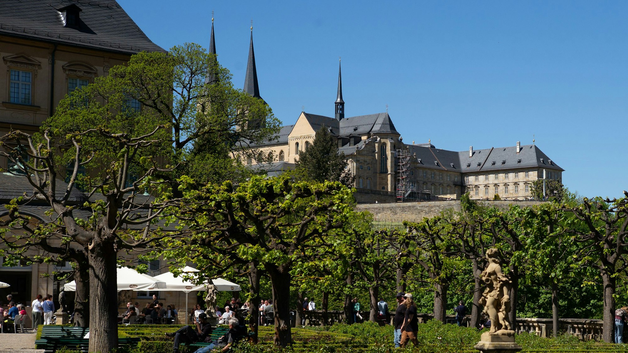 Blick auf ein Klostern, darunter ein Biergarten in einem Park