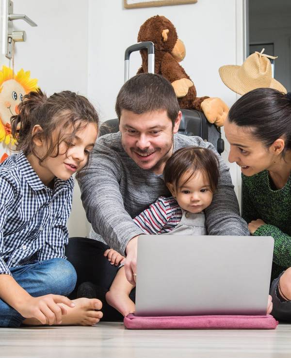Eine Familie sitzt vor dem Laptop und bucht eine Reise