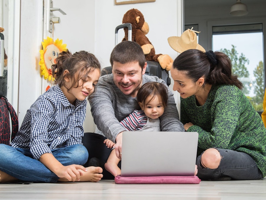 Eine Familie sitzt vor dem Laptop und bucht eine Reise