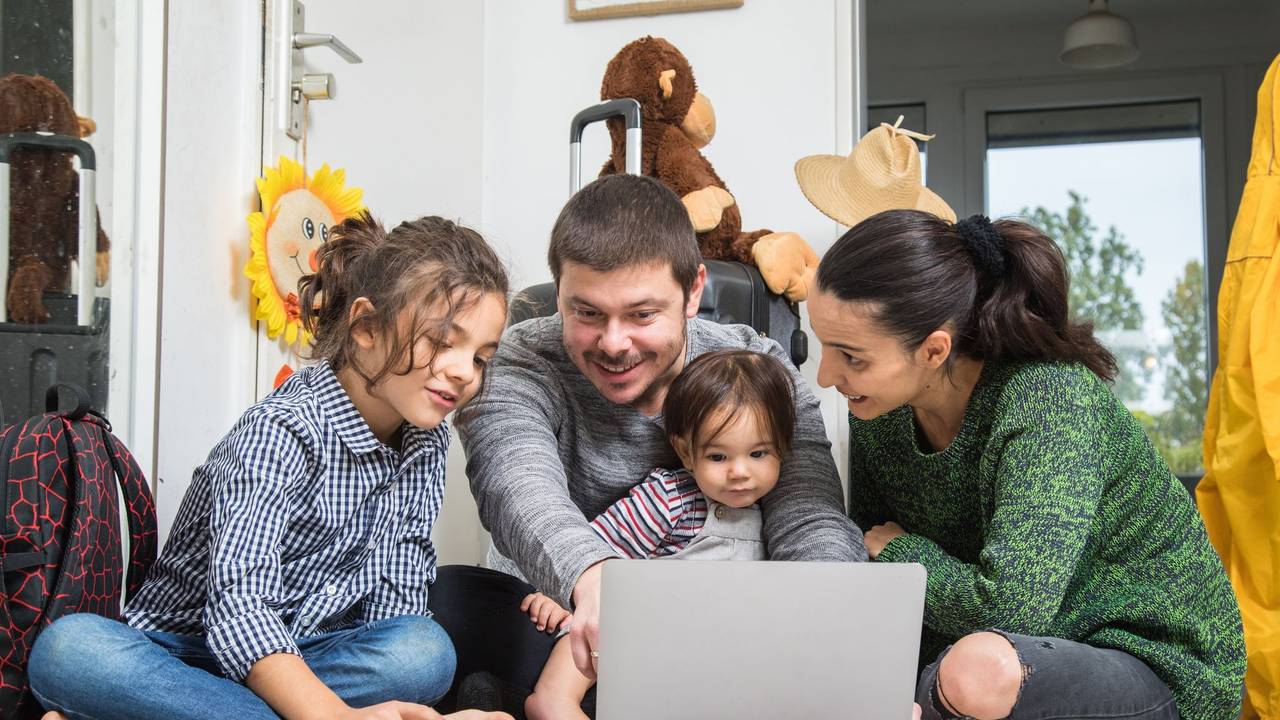 Eine Familie sitzt vor dem Laptop und bucht eine Reise
