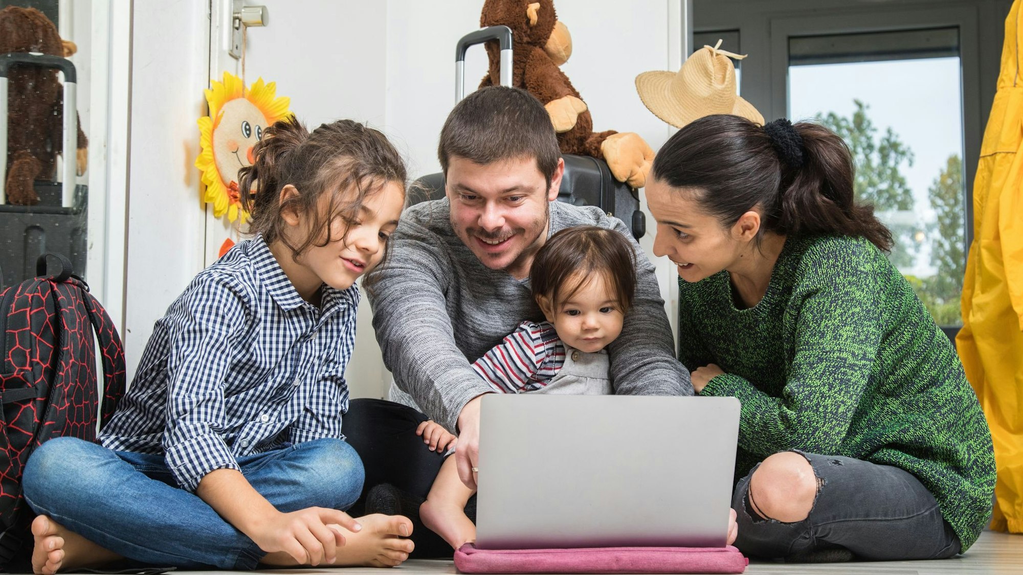 Eine Familie sitzt vor dem Laptop und bucht eine Reise