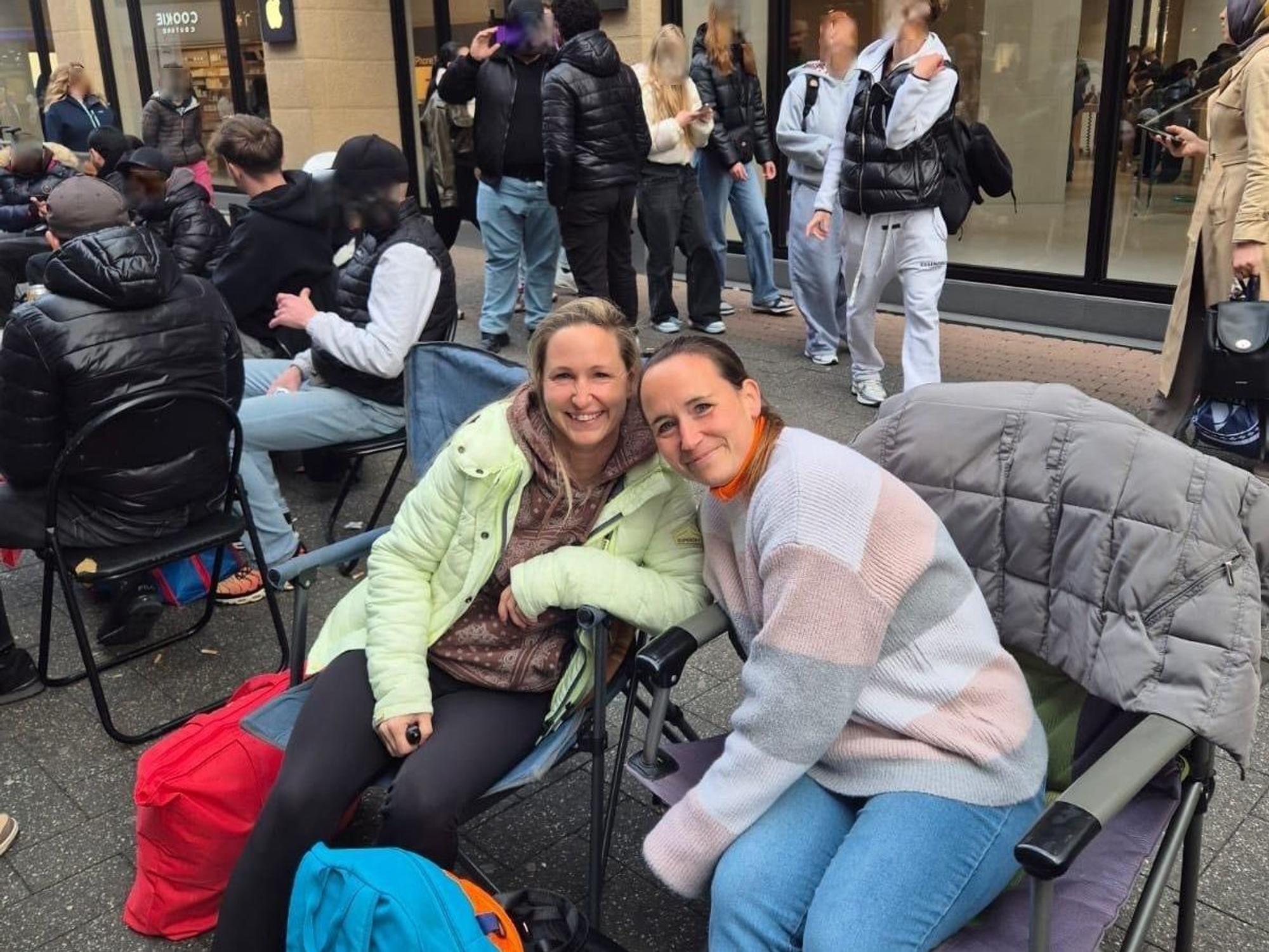 Melanie Kilbinger und ihre Schwester sitzen auf Campingstühlen in einer Reihe wartender Personen.
