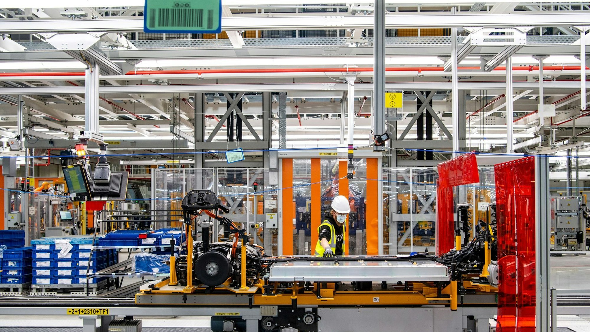 Arbeiter arbeitet mit der Batterie am Unterboden eines E-Autos