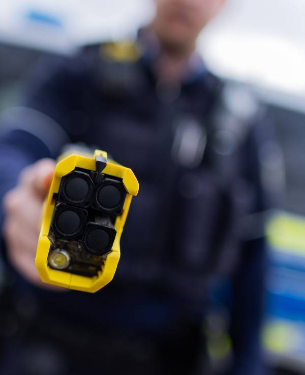 Ein Polizist hält einen Taser in die Kamer.