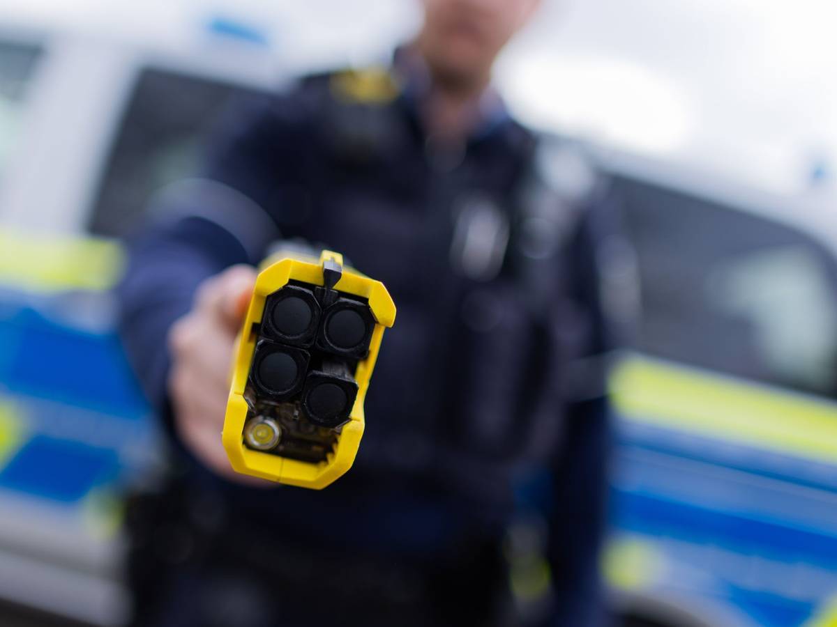 Ein Polizist hält einen Taser in die Kamer.