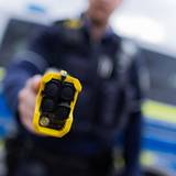 Ein Polizist hält einen Taser in die Kamer.