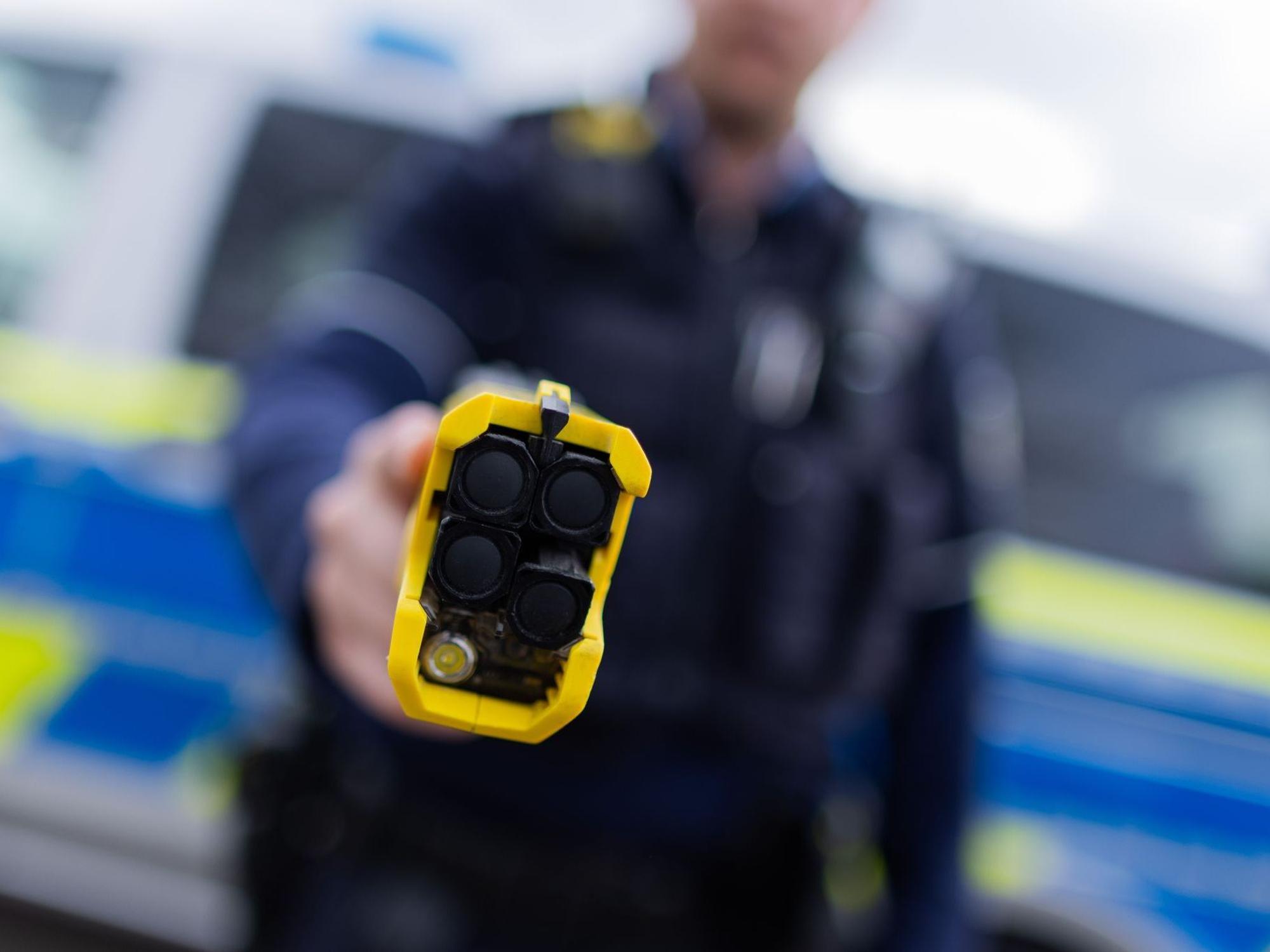Ein Polizist hält einen Taser in die Kamer.