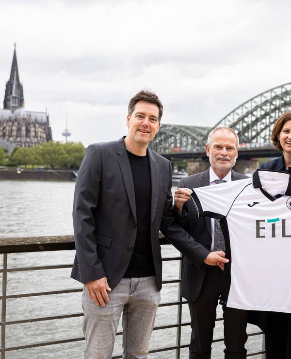 Von links: Axel Freisewinkel (Geschäftsführer FC Viktoria Köln 1904 Spielbetriebs GmbH), Christoph Malzkorn (Vorstand ETL-Gruppe), Nadine Lais (Geschäftsführerin ETL Service GmbH), Eric Bock (Geschäftsführer FC Viktoria Köln 1904 Spielbetriebs GmbH) am Rhein vor dem Dom und der Hohenzollernbrücke.