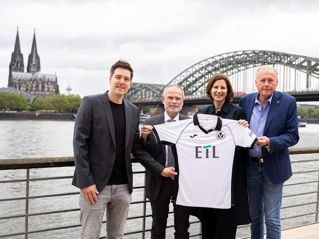 Von links: Axel Freisewinkel (Geschäftsführer FC Viktoria Köln 1904 Spielbetriebs GmbH), Christoph Malzkorn (Vorstand ETL-Gruppe), Nadine Lais (Geschäftsführerin ETL Service GmbH), Eric Bock (Geschäftsführer FC Viktoria Köln 1904 Spielbetriebs GmbH) am Rhein vor dem Dom und der Hohenzollernbrücke.