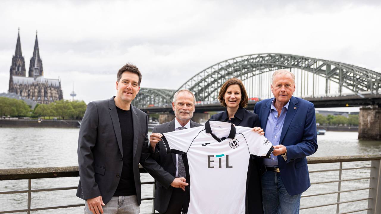 Von links: Axel Freisewinkel (Geschäftsführer FC Viktoria Köln 1904 Spielbetriebs GmbH), Christoph Malzkorn (Vorstand ETL-Gruppe), Nadine Lais (Geschäftsführerin ETL Service GmbH), Eric Bock (Geschäftsführer FC Viktoria Köln 1904 Spielbetriebs GmbH) am Rhein vor dem Dom und der Hohenzollernbrücke.