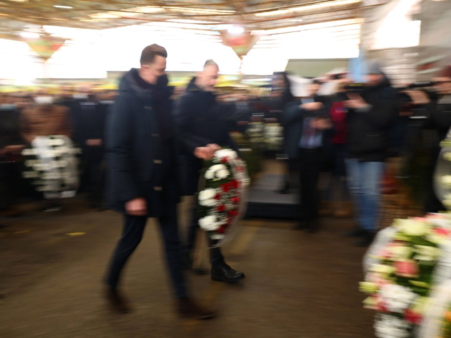Menschen mit Blumenkränzen bei Gedenkveranstaltung