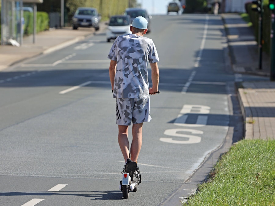 Eine Person fährt E-Scooter auf Straße
