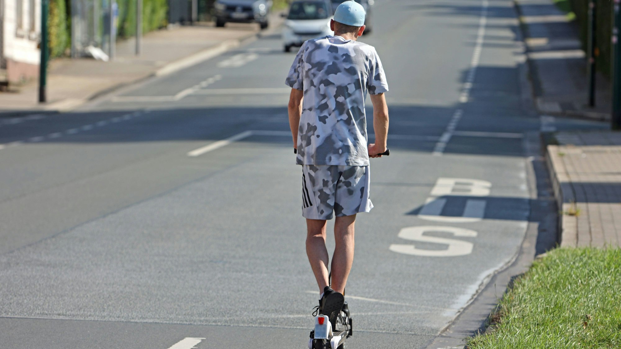 Eine Person fährt E-Scooter auf Straße