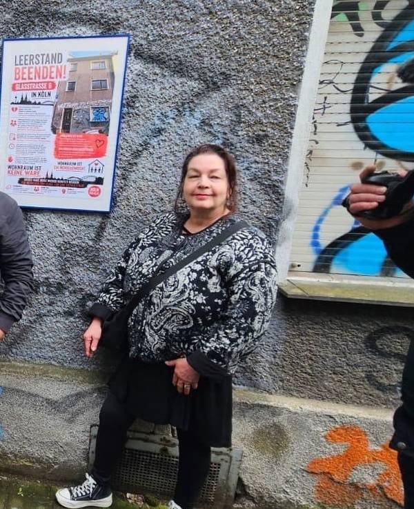 Drei Männer und eine Frau stehen vor einem Haus.
