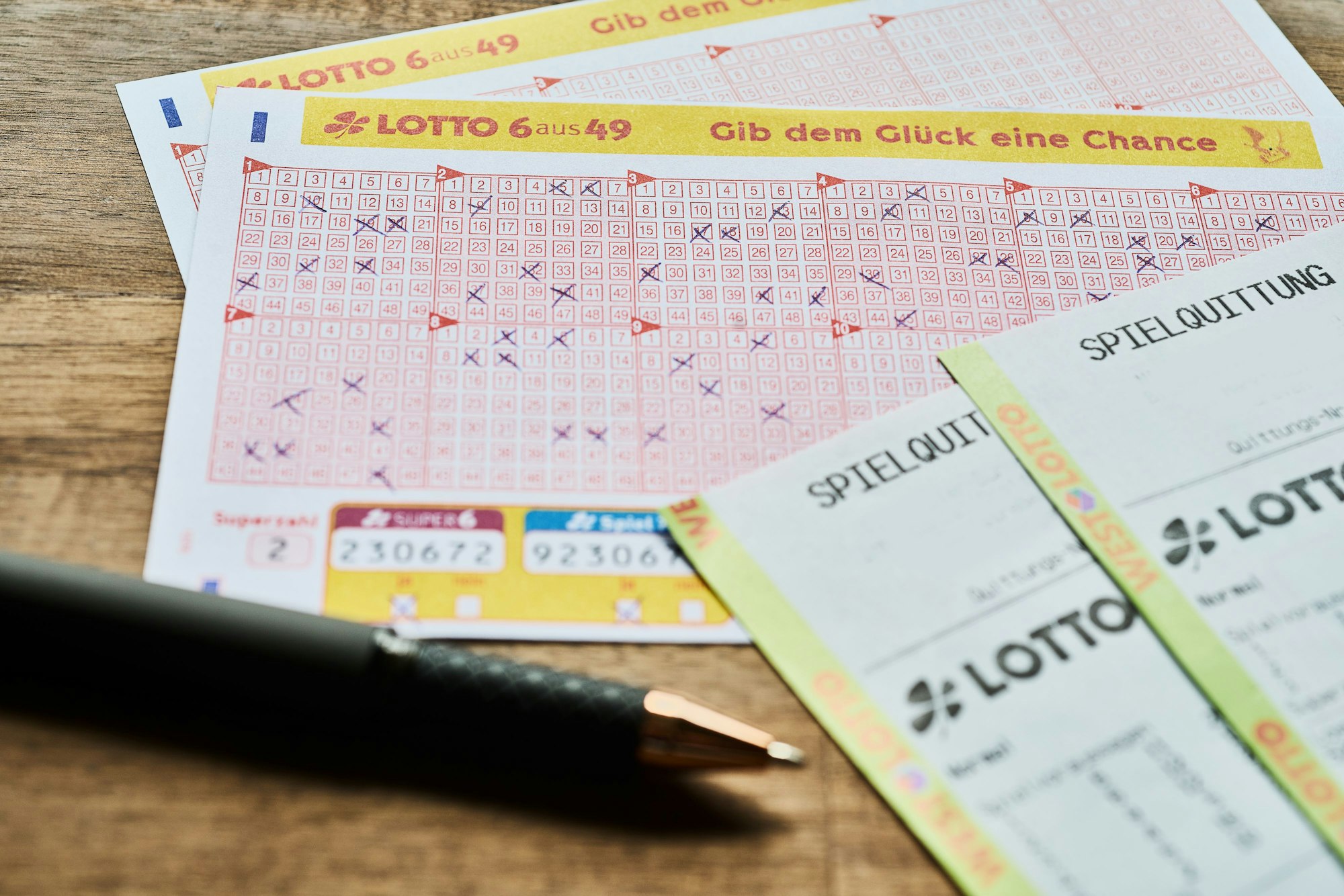 Auf einem Tisch liegt ein LOTTO 6aus49 Tippschein sowie die Spielquittung.