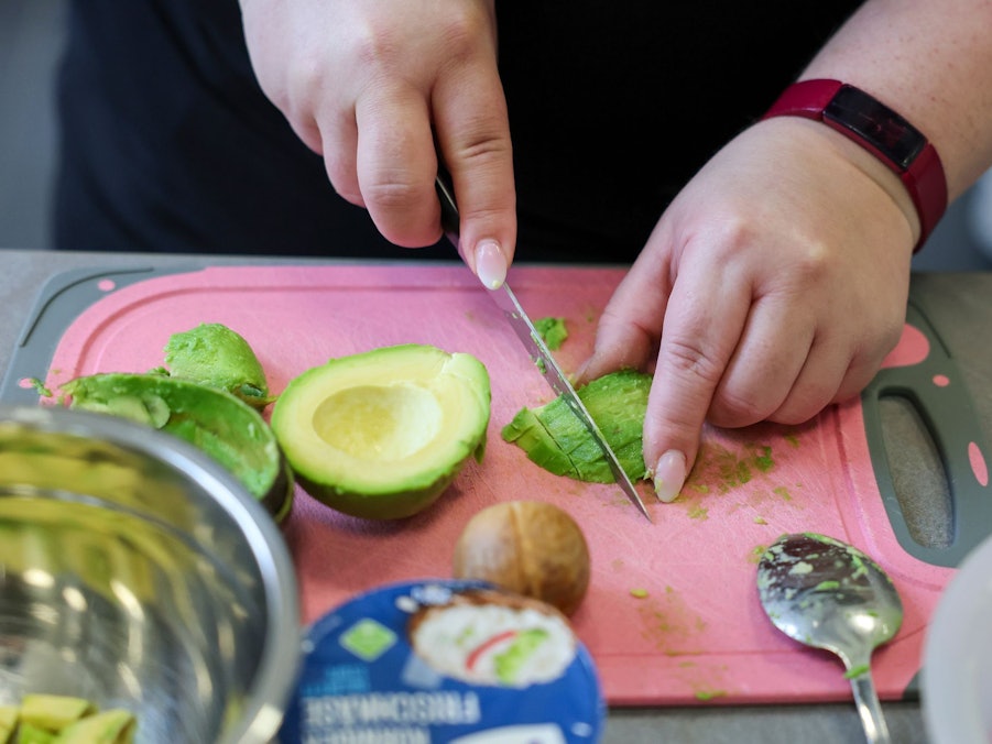 Eine übergewichtige Frau schneidet Avocado
