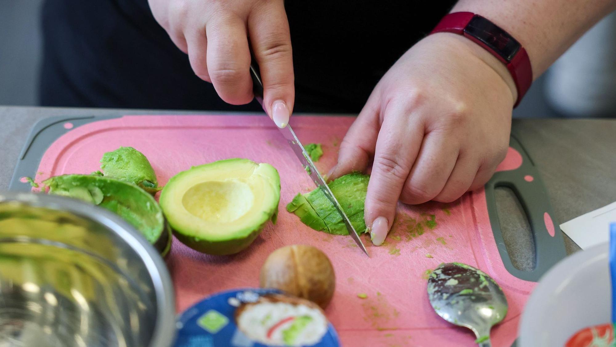Eine übergewichtige Frau schneidet Avocado