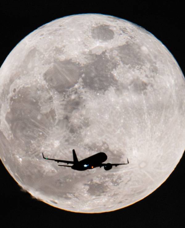 Ein Passagierflugzeug fliegt am Vollmond vorbei