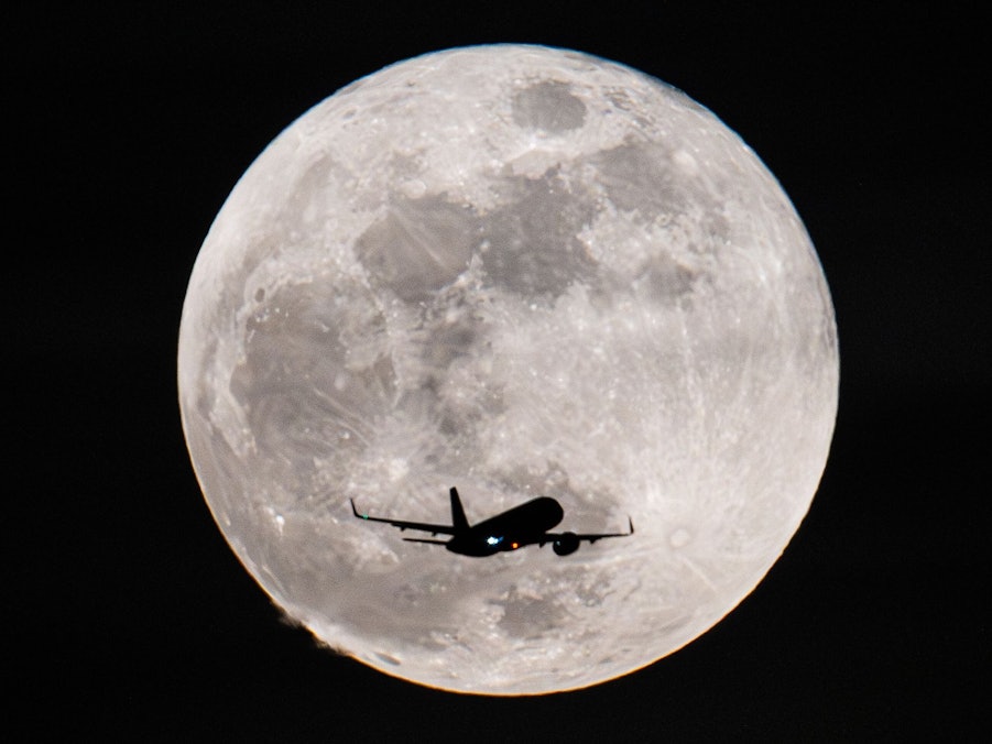 Ein Passagierflugzeug fliegt am Vollmond vorbei