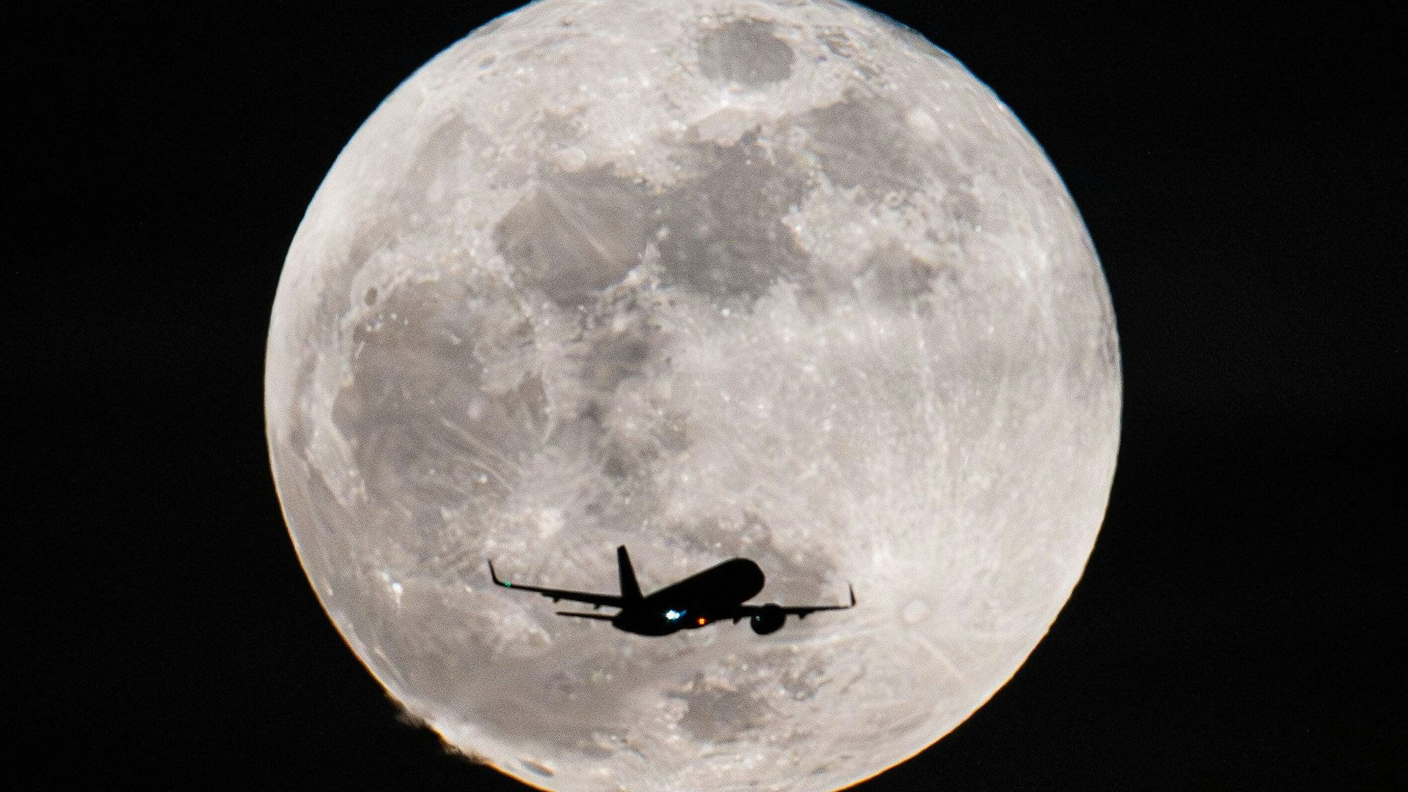 Ein Passagierflugzeug fliegt am Vollmond vorbei