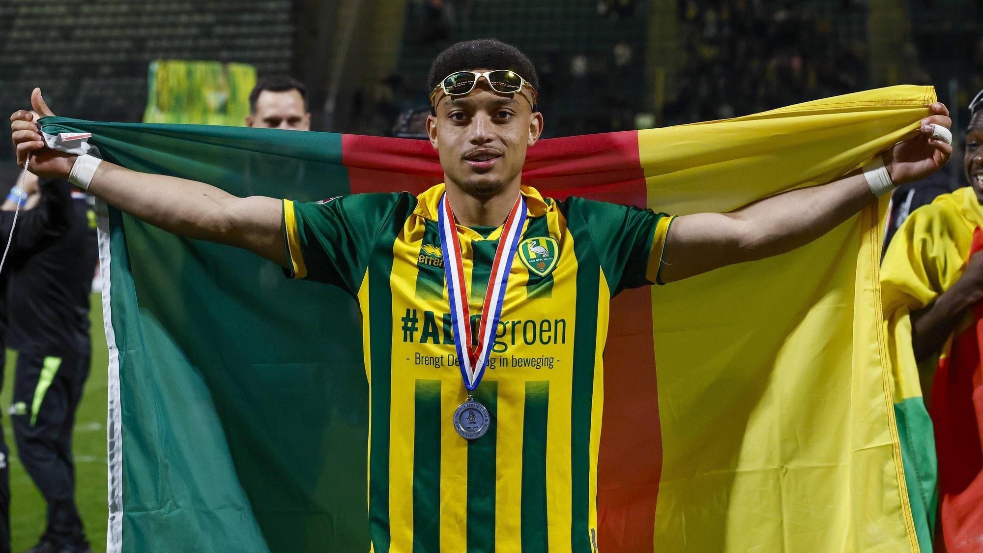 Steven van der Sloot breitet eine Kamerun-Flagge hinter sich aus.