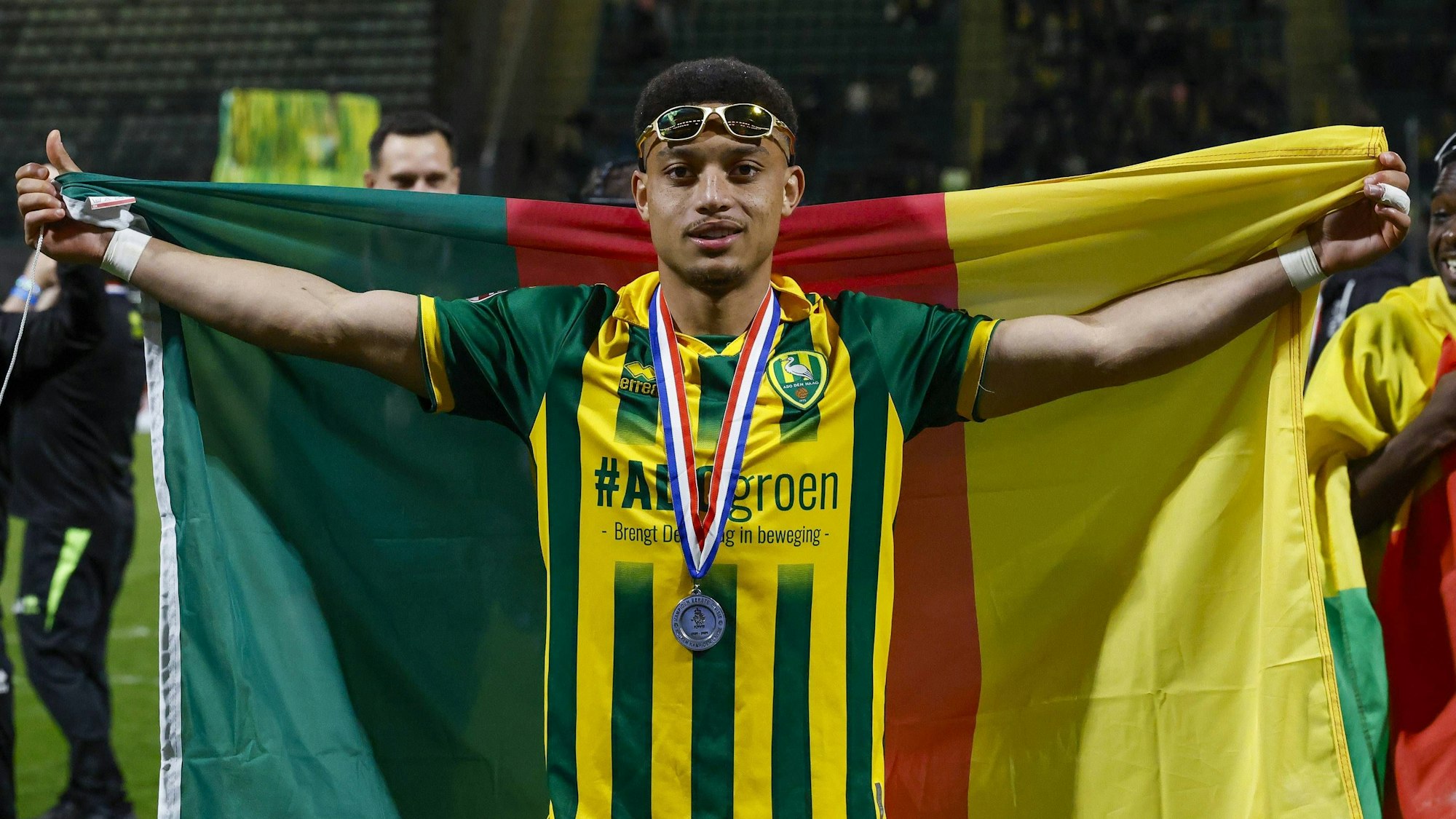 Steven van der Sloot breitet eine Kamerun-Flagge hinter sich aus.