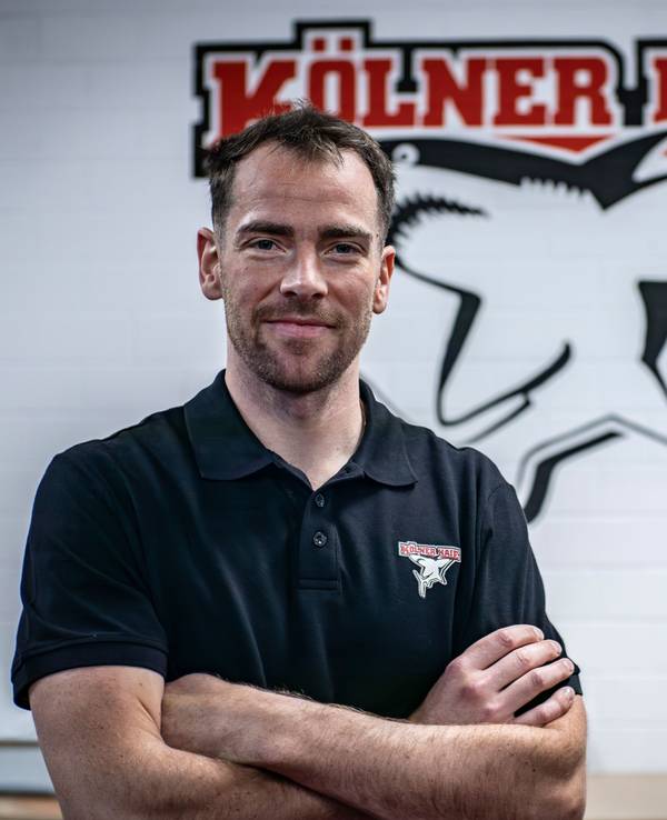 Marcel Noebels posiert vor dem Logo der Kölner Haie.