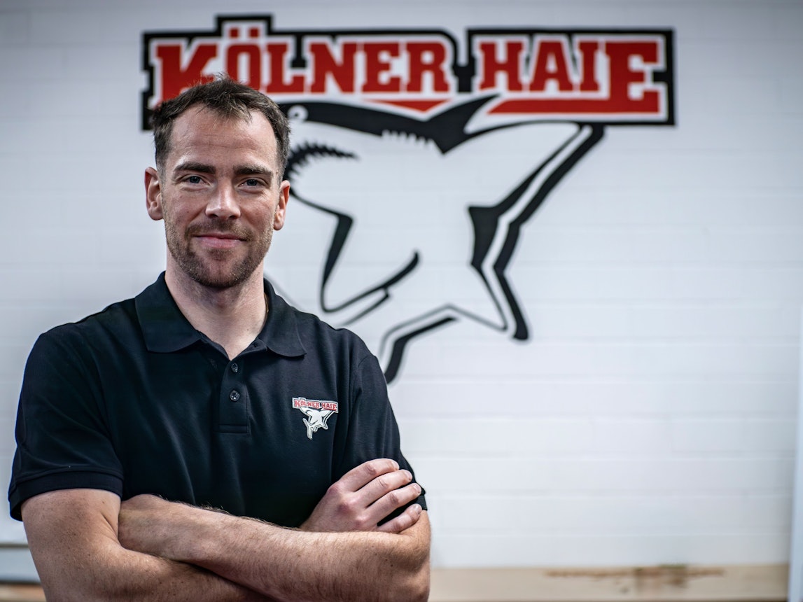 Marcel Noebels posiert vor dem Logo der Kölner Haie.