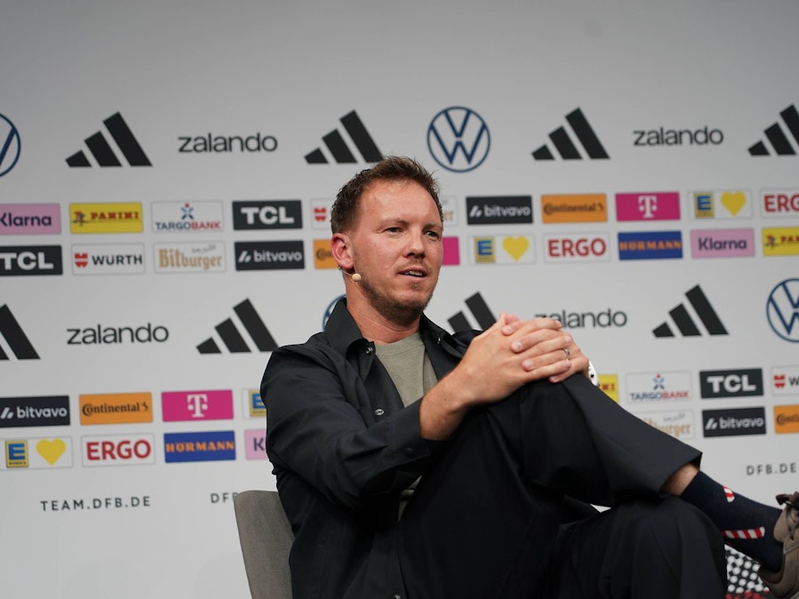 Julian Nagelsmann sitzt mit überschlagenen Beinen bei einer DFB-Pressekonferenz.