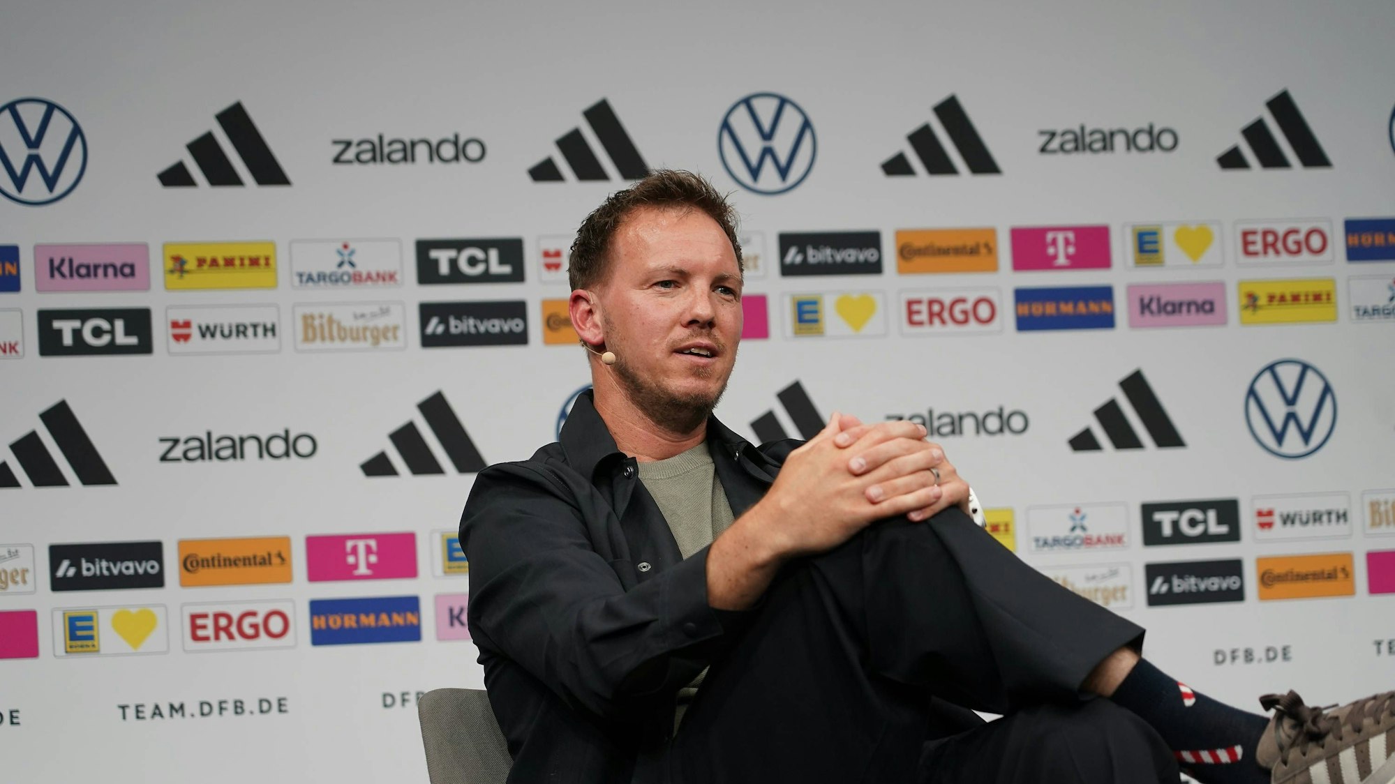 Julian Nagelsmann sitzt mit überschlagenen Beinen bei einer DFB-Pressekonferenz.