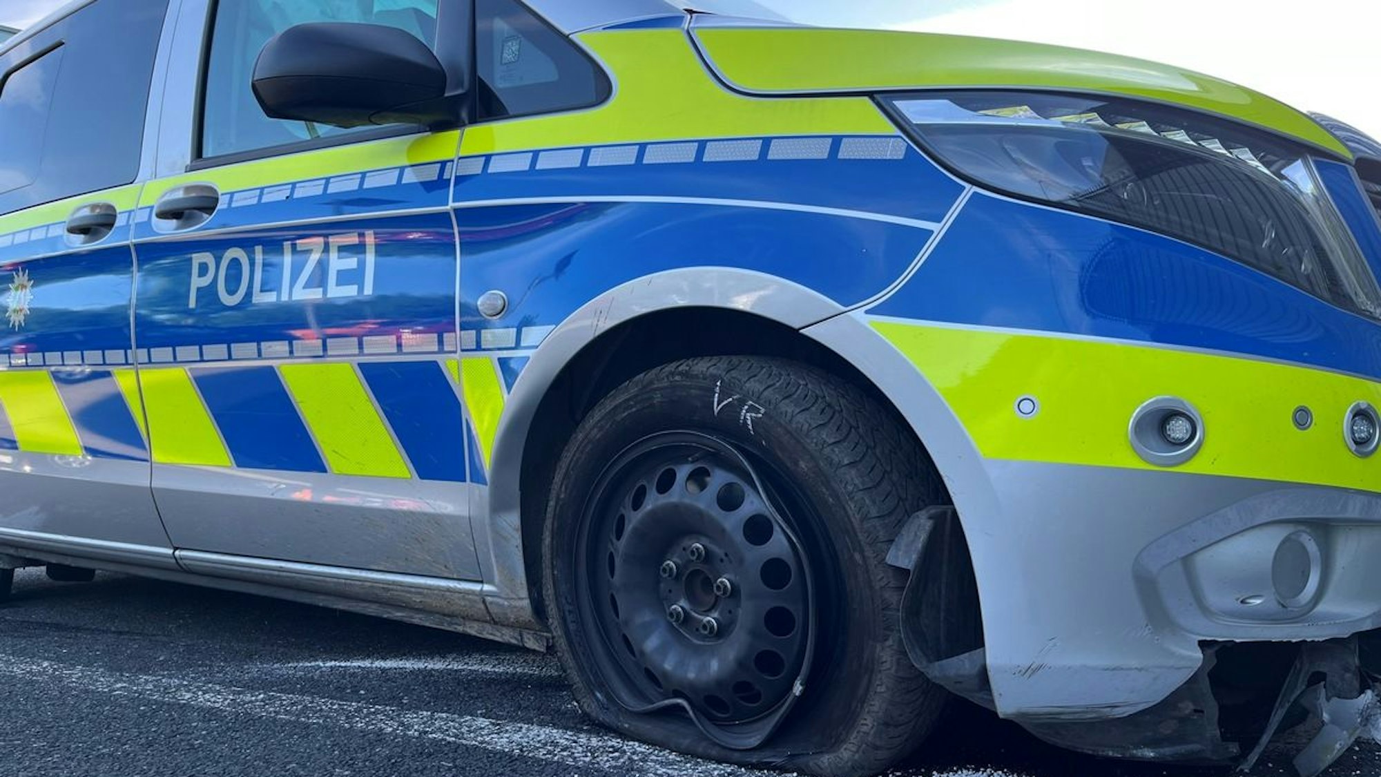 Ein beschädigter Streifenwagen der Polizei steht am Straßenrand.