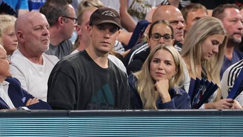 Anika Bissel und Manuel Neuer sitzen gemeinsam auf der Tribüne bei einem Handballspiel