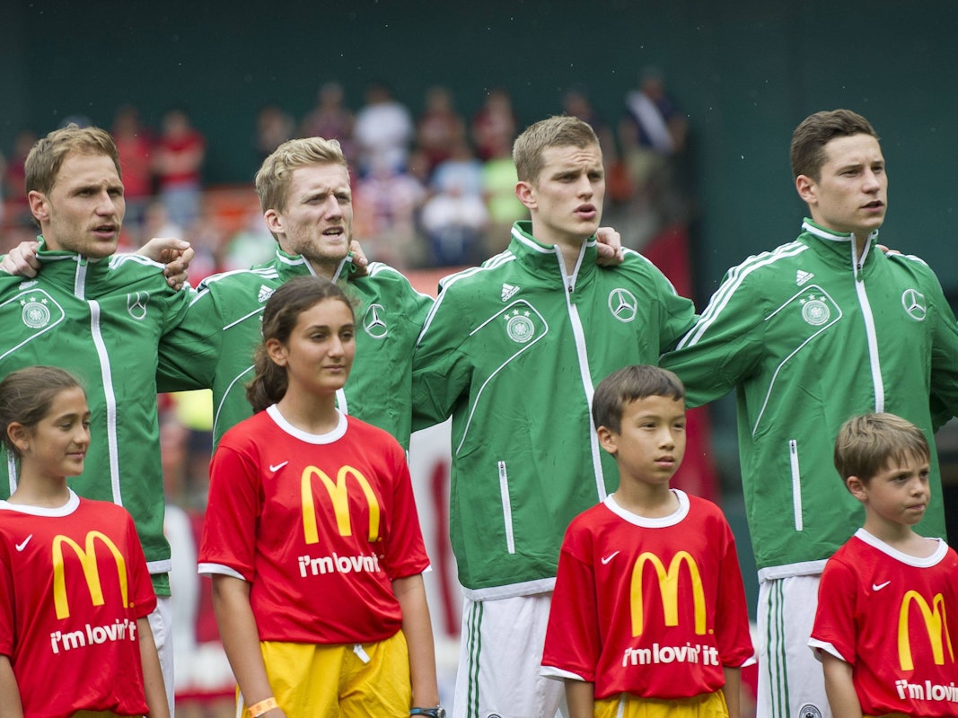 Von links nach rechts: Benedikt Höwedes, André Schürrle, Lars Bender und Julian Draxler singen auf dem Spielfeld die Hymne von Deutschland.