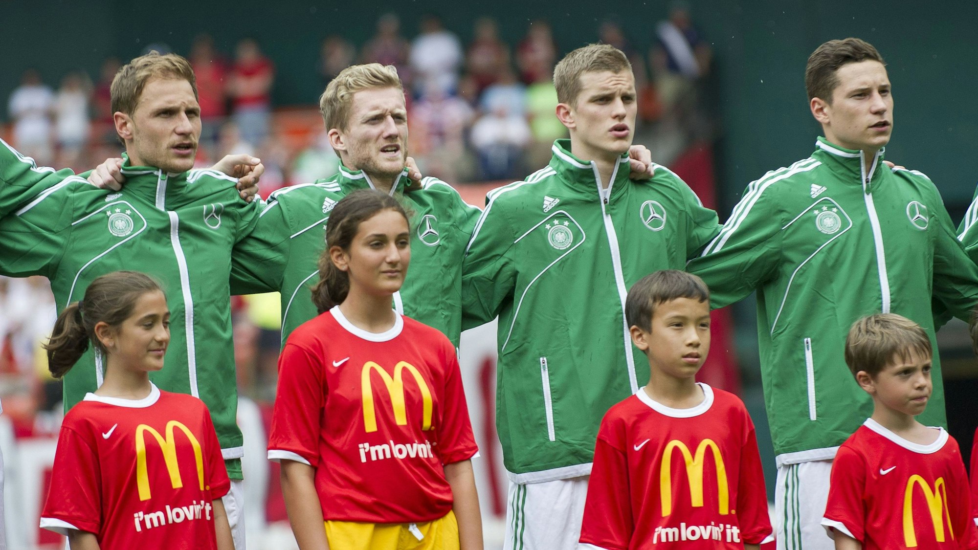 Von links nach rechts: Benedikt Höwedes, André Schürrle, Lars Bender und Julian Draxler singen auf dem Spielfeld die Hymne von Deutschland.