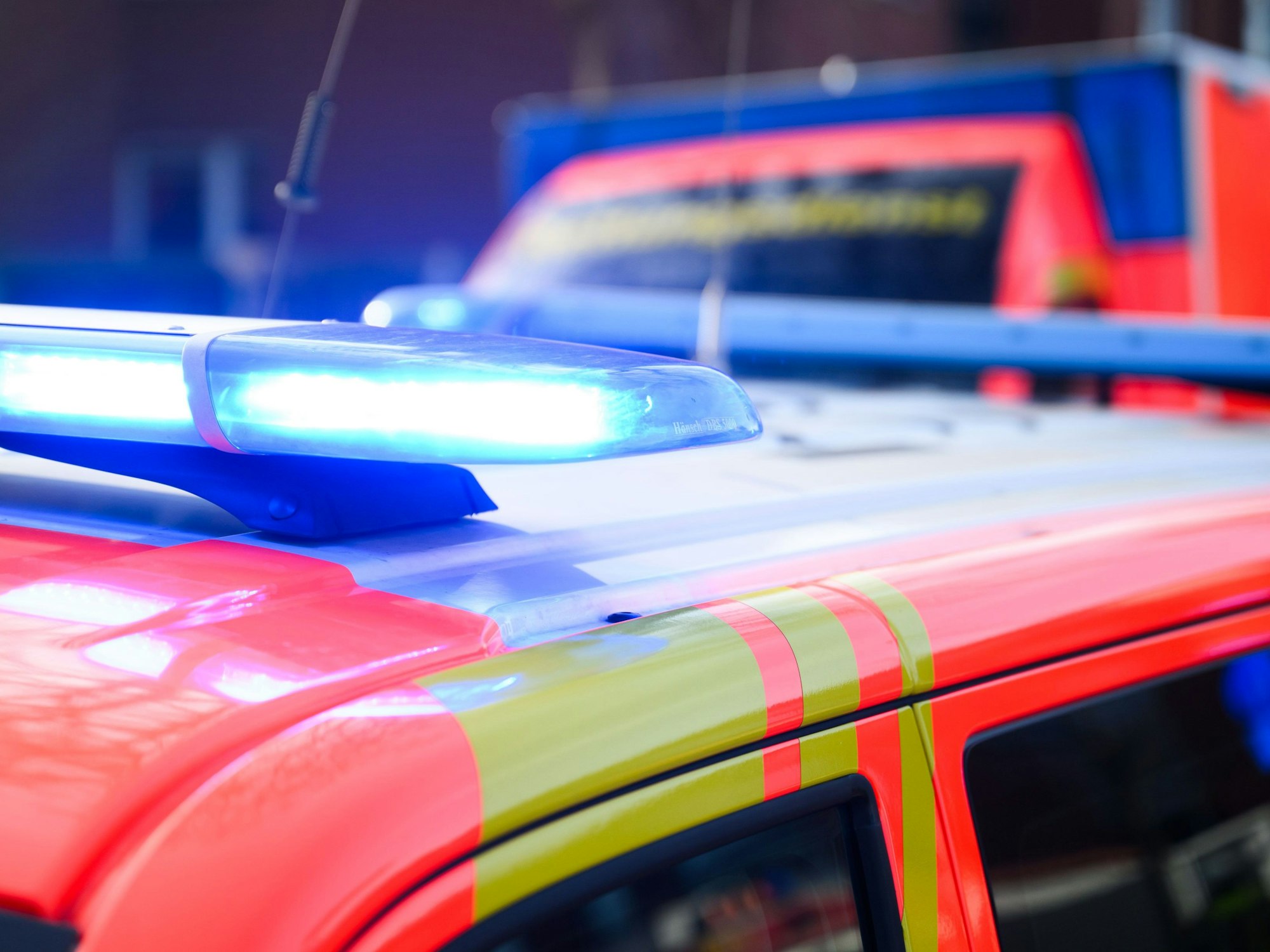 Blaulichter leuchten an einer Einsatzstelle auf einem Notarztfahrzeug und einem Rettungswagen.