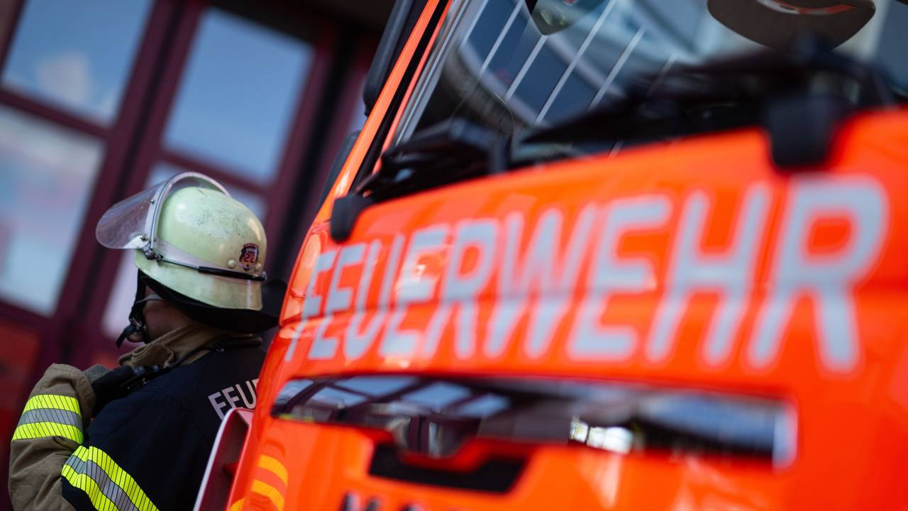 Eine Einsatzkraft der Feuerwehr steht neben einem Einsatzfahrzeug der Feuerwehr.