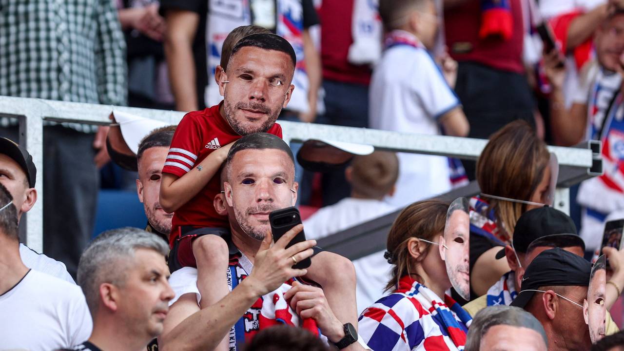 Zwei Fans mit Poldi-Masken auf der Tribüne.