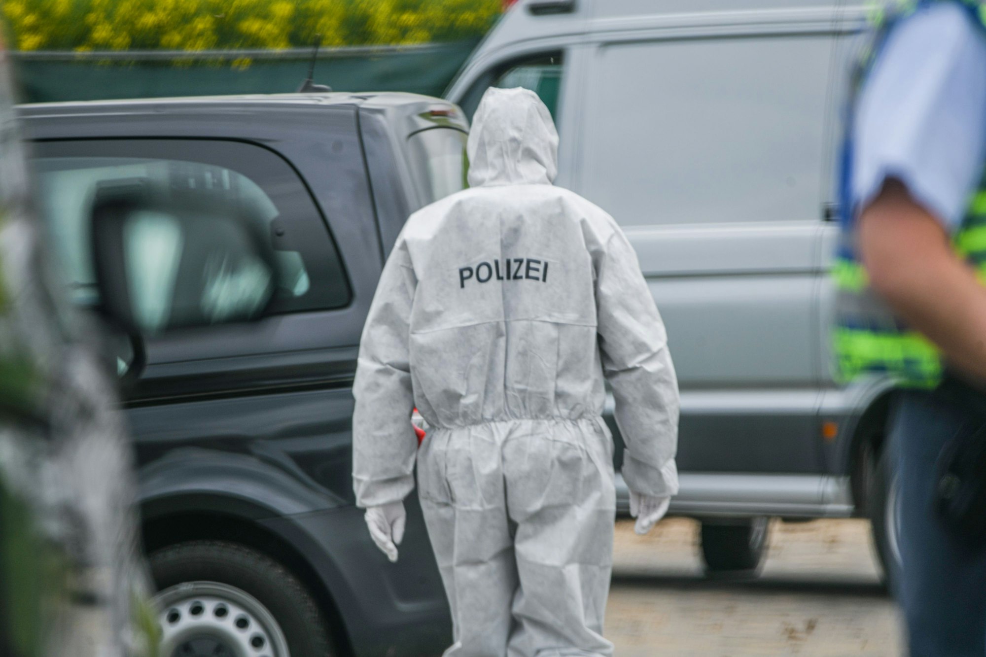 Eine Person, die einen Ganzkörperanzug der Spurensicherung trägt, geht auf ein Fahrzeug zu.