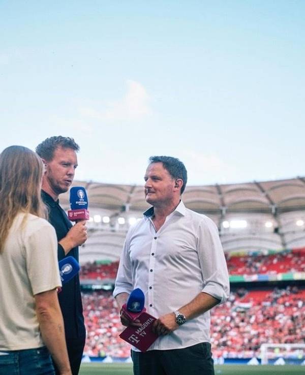 Moderator Thomas Wagner steht mit seinem Mikrofon am Spielfeldrand und spricht mit Julian Nagelsmann.
