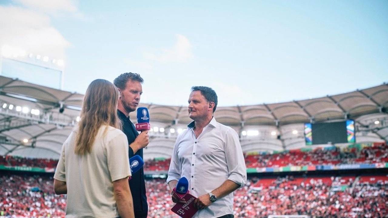 Moderator Thomas Wagner steht mit seinem Mikrofon am Spielfeldrand und spricht mit Julian Nagelsmann.
