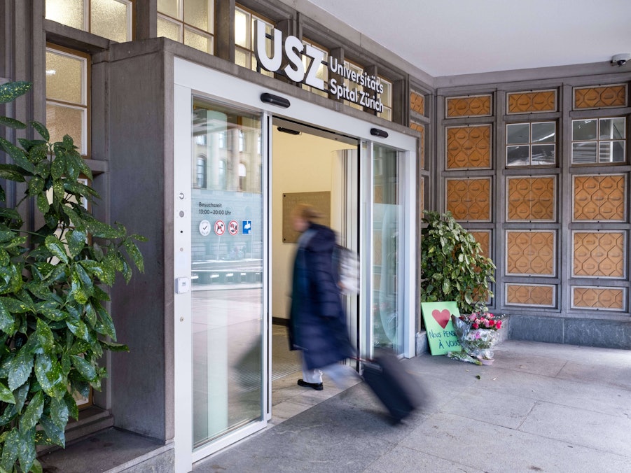 Gebäudeeingang mit Person, Blumen und Schild