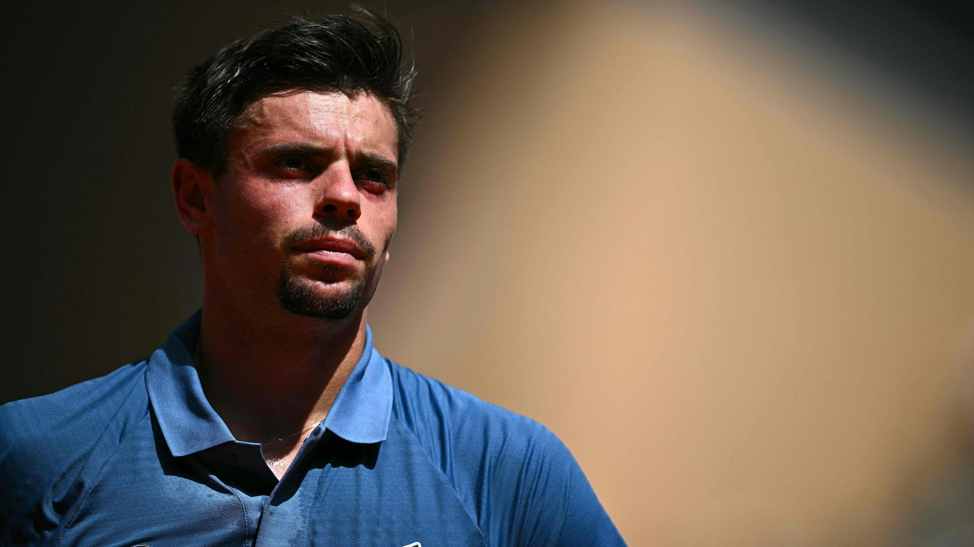 Arthur Géa trägt bei einem Tennis-Match ein blaues Poloshirt.