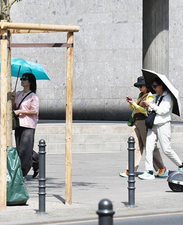 Touristen schützen sich mit Regenschirmen vor der Sonne.
