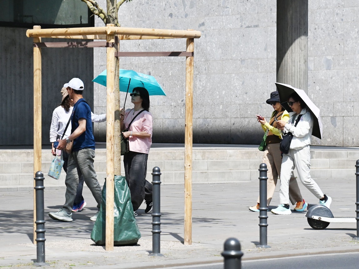 Touristen schützen sich mit Regenschirmen vor der Sonne.