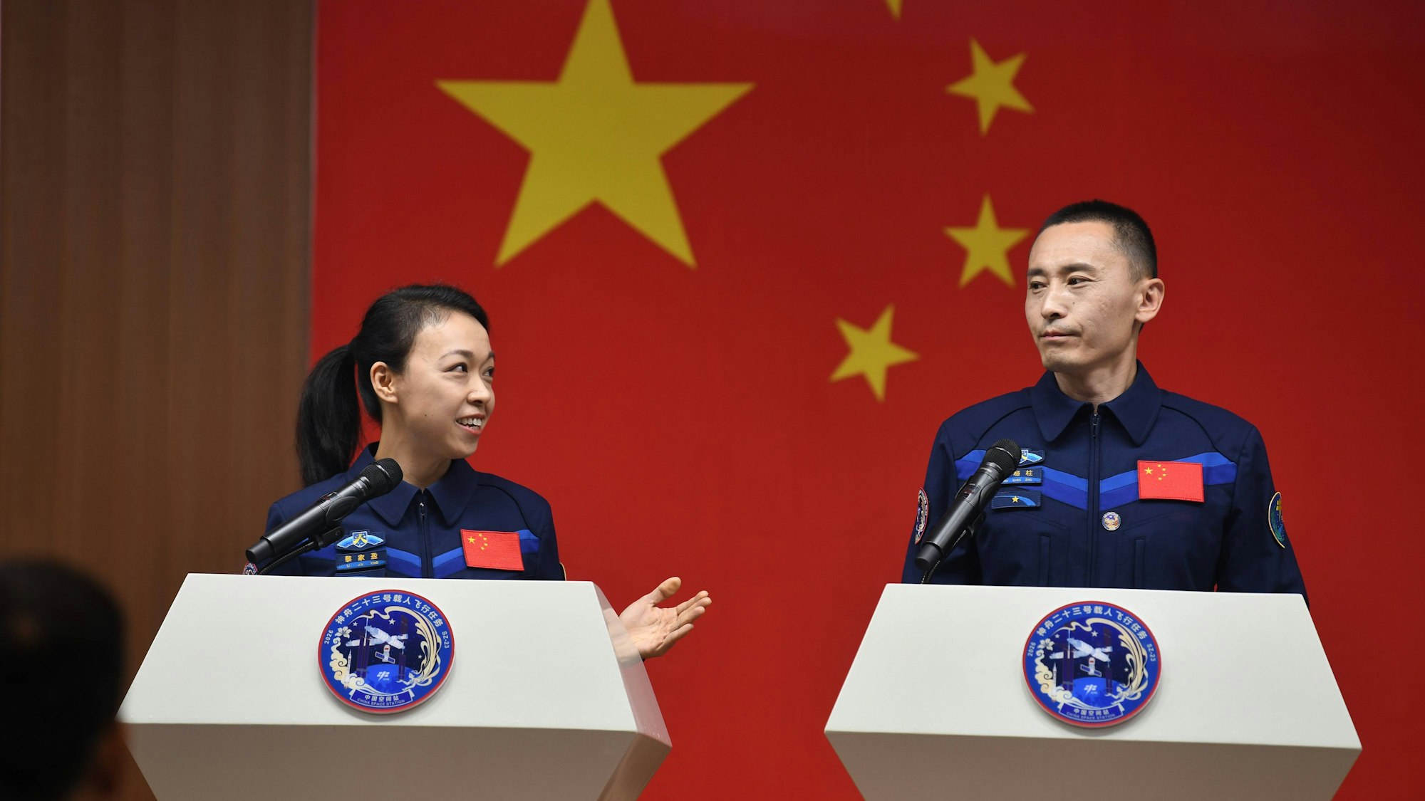 Astronauten Li Jiaying & Zhu Yangzhu sprechen vor Flagge
