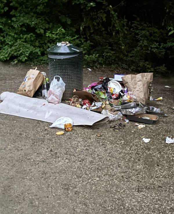 Müll liegt um einen Mülleimer verstreut auf dem Boden.