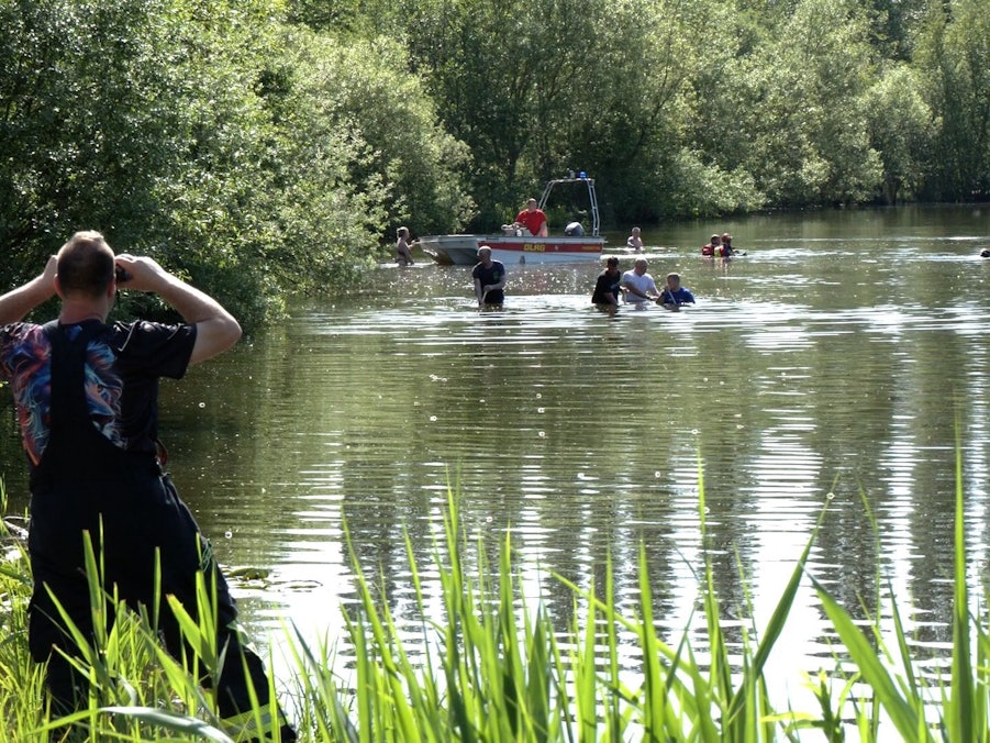 Einsatzkräfte und Helfer am See mit Boot