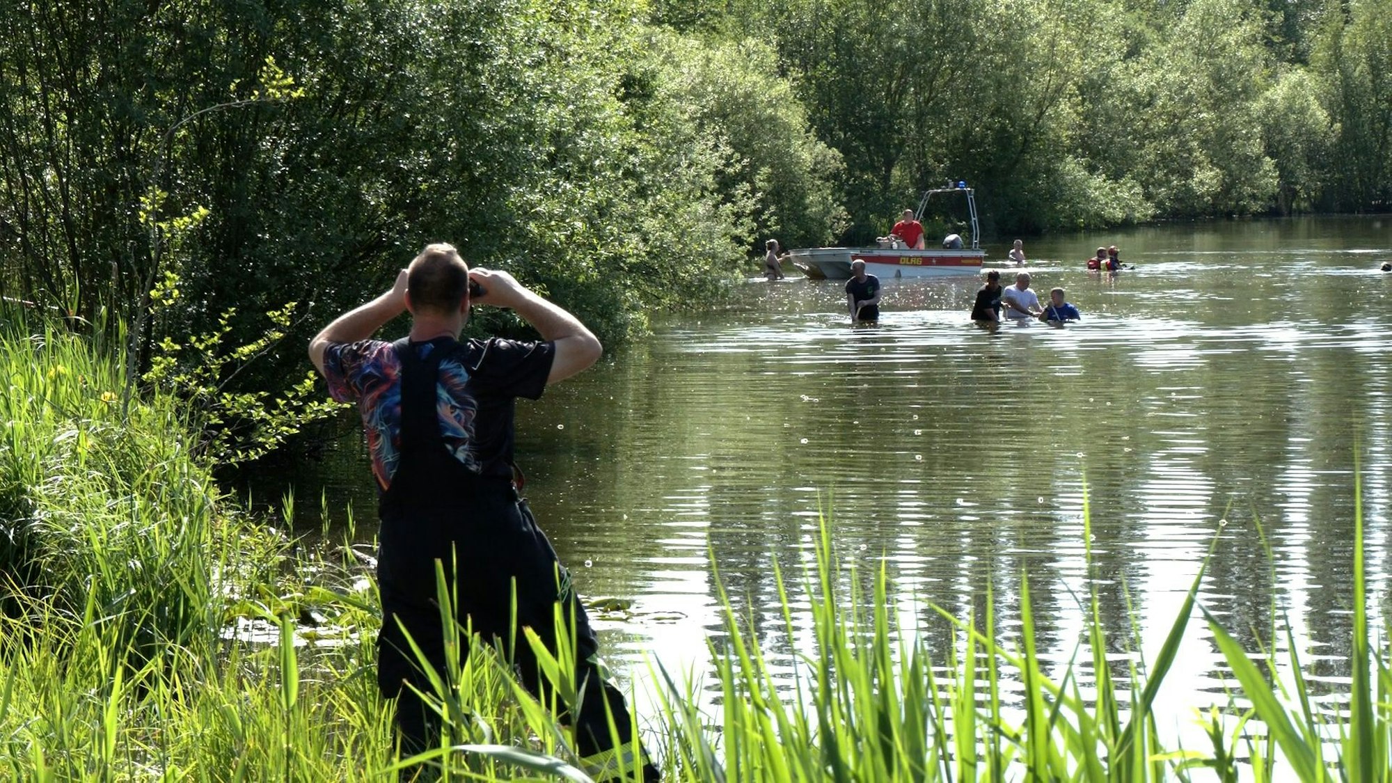 Einsatzkräfte und Helfer am See mit Boot