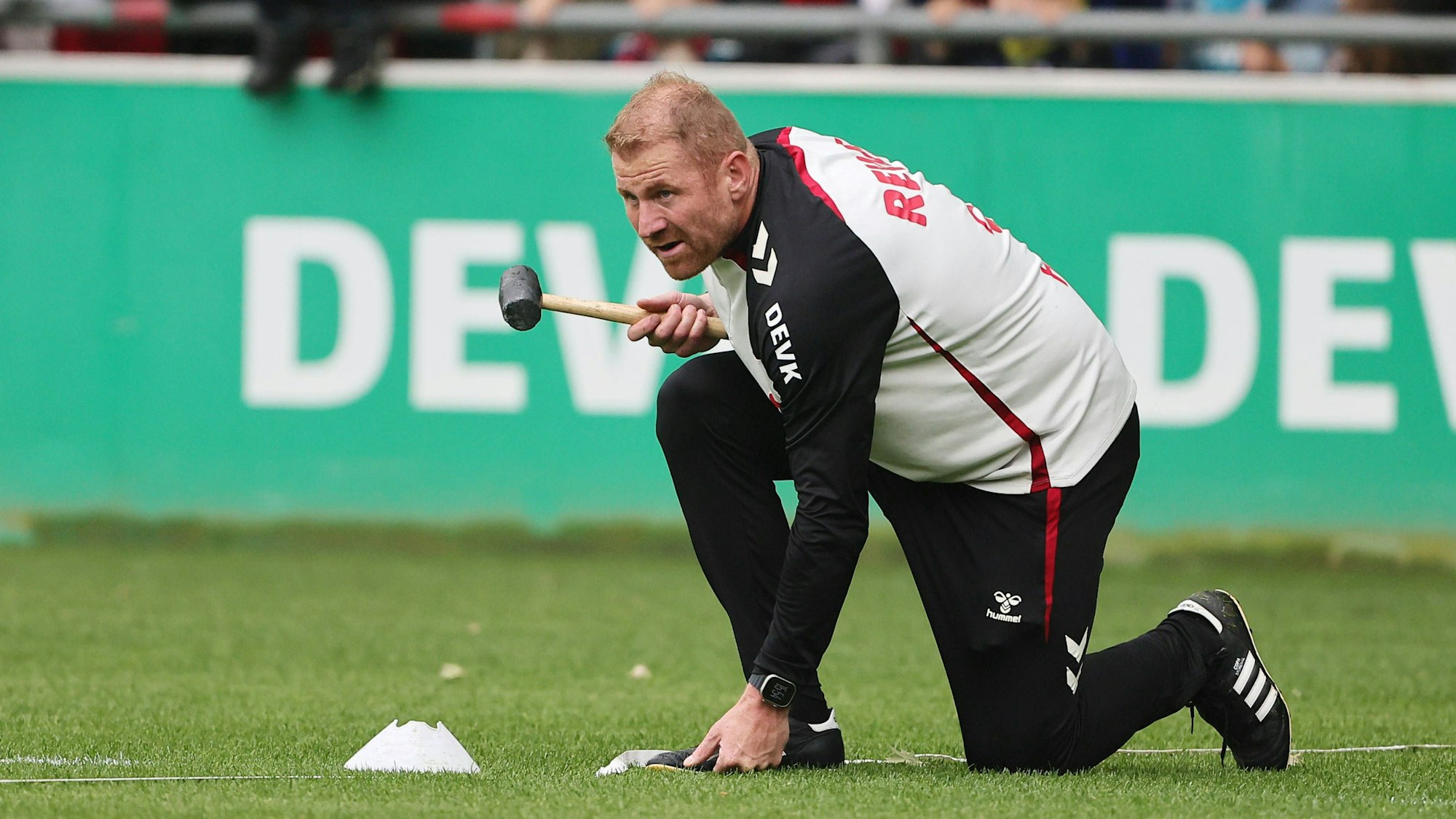 Lukas Sinkiewicz hält auf dem Platz einen Hammer in der Hand.